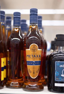 Büyüleyici bir Metaxa 7 şişesi, bir mağaza ortamında diğer içecekler arasında zarif bir şekilde sergilenen Yunan ruhlarının özünü sunuyor. - FRANKFURT, Almanya - 21 Mart 2025