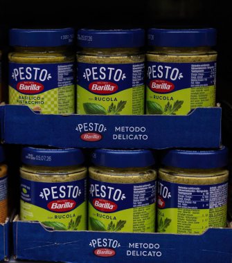 Barilla pesto sosu kavanozlarının düzenli bir düzenlemesi, taze malzemeler ve canlı renkler sergilenmesi, çeşitli yemekleri zengin ve aromatik tatlarla geliştirmek için mükemmel. - FRANKFURT, Almanya - 21 Mart 2025