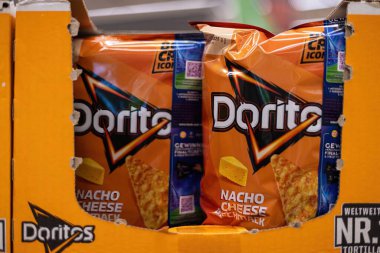 Bu resim, Doritos nacho peynirli atıştırmalık paketlerini perakende rafında belirgin bir şekilde sergiliyor, parlak ambalajlarını ve abur cubur aşıkları için karşı konulmaz çekiciliklerini sergiliyor. - FRANKFURT, Almanya - 21 Mart 2025