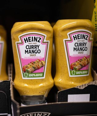 Heinz Curry Mango sosu şişeleri market rafında parlıyor ve çeşitli tavuk ve domuz eti yemekleri için ideal olan eşsiz lezzet karışımlarını sergiliyorlar. - FRANKFURT, Almanya - 21 Mart 2025