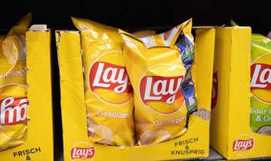 Lay 'in tuzlu patates cipsleri göz alıcı bir vitrin kutusunda sunuluyor ve raflarda markaların özel ürünlerini sergiliyor. - FRANKFURT, Almanya - 21 Mart 2025