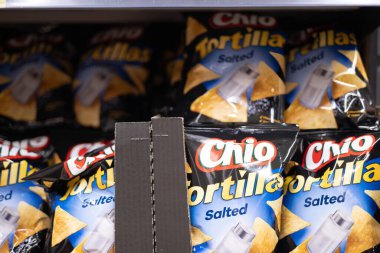 Bu resim Chio Tortillas Tortillas tuzlu poşetleri bir mağaza rafında düzgünce düzenlenmiş, çekici ambalaj tasarımı vurgulanıyor. - FRANKFURT, Almanya - 21 Mart 2025
