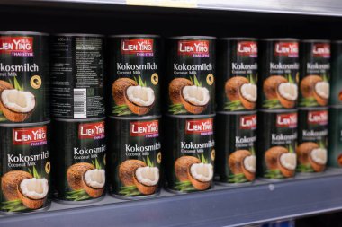 Mutfak meraklıları yemeklerini zenginleştirmek için bir mağaza rafında düzenli hindistan cevizi sütü konserveleri. - FRANKFURT, Almanya - 21 Mart 2025