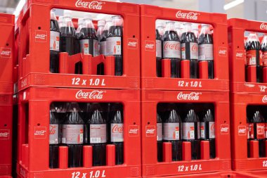 Kırmızı sandıkların üzerinde markanın ikonik renk şemasını ve ambalajını vurgulayan düzgünce düzenlenmiş bir Coca-Cola şişesi yığını. - FRANKFURT, Almanya - 21 Mart 2025