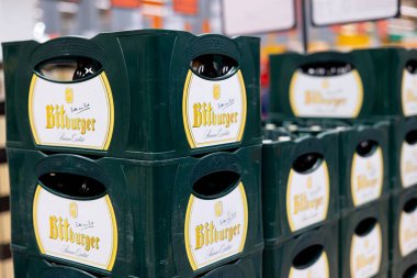 Düzenli bir Bitburger bira şişesi yığını. Perakende satış ortamında geleneksel yeşil ambalajlar sergileniyor. - FRANKFURT, Almanya - 21 Mart 2025