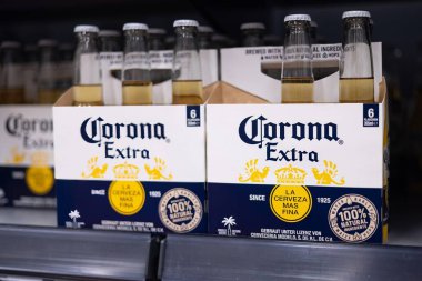 Altılı paket Corona Extra şişesi, markanın ikonik tasarımı ve plaj kenarı rahatlama deneyimi sergileniyor. - FRANKFURT, Almanya - 21 Mart 2025