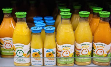 Bu canlı portakal suyu şişesi, diğer raftakiler arasında göze çarpıyor, parlak rengini ve sağlıklı tüketiciler için canlandırıcı cazibesini sergiliyor. - FRANKFURT, Almanya - 21 Mart 2025