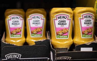 Heinz Curry Mango sosu şişeleri market rafında parlıyor ve çeşitli tavuk ve domuz eti yemekleri için ideal olan eşsiz lezzet karışımlarını sergiliyorlar. - FRANKFURT, Almanya - 21 Mart 2025