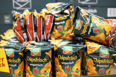 Canlı bir cips torbası gösterisi, farklı tatlar ve tasarımlar sergileniyor bir markette abur cubur aşıkları için. - FRANKFURT, Almanya - 21 Mart 2025