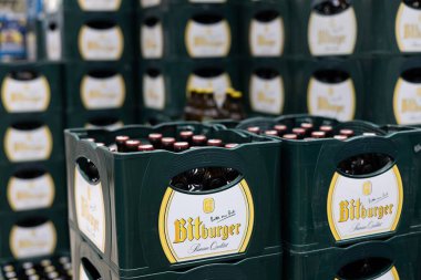 Düzenli bir Bitburger bira şişesi yığını. Perakende satış ortamında geleneksel yeşil ambalajlar sergileniyor. - FRANKFURT, Almanya - 21 Mart 2025