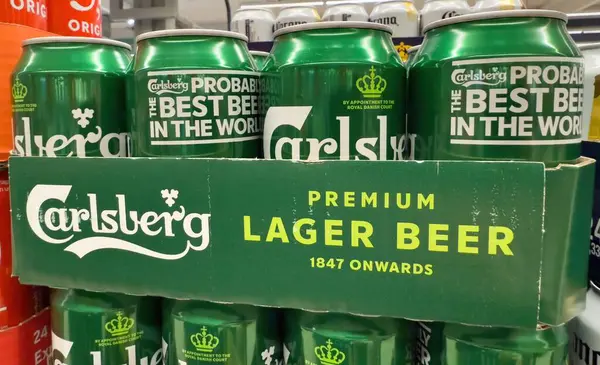 Bir yığın canlı yeşil Carlsberg bira kutuları, arkadaşlar arasında günlük toplantılara ve sosyal eğlenceye davetiye çıkarıyor. - FRANKFURT, Almanya - 21 Mart 2025
