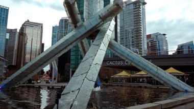 VANCOUVER, CANADA - 11 Nisan 2017 - Modern cam ve çelik olimpiyat kazanı Jack Poole Plaza 'da yanıyor Vancouver şehrinin silueti ve arka planında Kaktüs Club Cafe English Bay