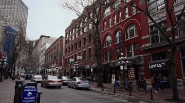 VANCOUVER, CANADA - 11 Nisan 2017 - Otomobilleri Vancouver, Kanada 'da miras binalarının yanından geçen Cobblestone Caddesi