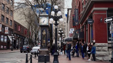 VANCOUVER, CANADA - 11 Nisan 2017 - Kanada 'nın Vancouver kentindeki Gastown kaldırımında duran turistler ünlü buharlı saate bakıyorlar
