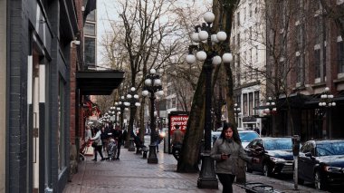 VANCOUVER, CANADA - 11 Nisan 2017 - Bulutlu bir günde Kanada 'nın Vancouver kentindeki Water Street' te yürüyen insanlar