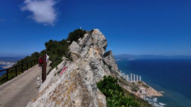 Güneşli bir günün tadını çıkaran turistler Cebelitarık 'ta yüksek irtifa manzaralı bir yolda yürüyor, kaya ve Akdeniz' in nefes kesici manzaralarını sunuyorlar - GIBRALTAR, İngiltere - 31 Mart 2025