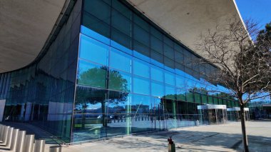 Gibraltar Uluslararası Havalimanı modern cam cephesini gözler önüne seriyor mavi gökyüzünü ve etrafındaki ağaçları yansıtıyor - GIBRALTAR, İngiltere - 31 Mart 2025