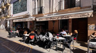 İspanya 'nın Ronda kentindeki kaldırım kafesinde dinlenen turistler ve yerel halk güneşli havanın tadını çıkarıyorlar - RONDA, İspanya - 28 Mart 2025