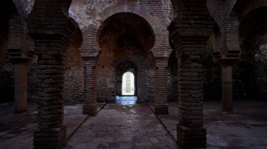 Ronda, İspanya 'da antik Arap hamamlarında, tuğla sütunlar ve at nalı kemerleri sergileniyor, bir kapıdan geçen ışık sahneyi aydınlatıyor - RONDA, SPAIN - 28 Mart 2025