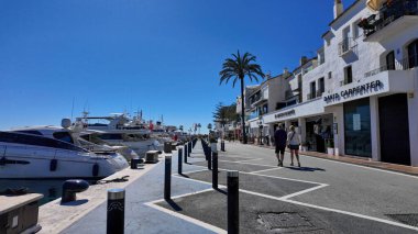 Marbella, İspanya 'da, lüks yatların ve beyaz binaların yanında yürüyen turistler - MARBELLA, İspanya - 30 Mart 2025