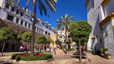 İspanya 'nın Marbella kentindeki Plaza de los Naranjos' da yürüyen turistler güneşli bir günün tadını çıkarıyorlar - MARBELLA, İspanya - 30 Mart 2025