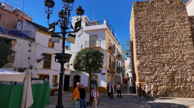 İspanya 'nın Marbella kentinde yürüyüş yapan turistler, büyüleyici beyaz binaları ve tarihi şehir duvarları - MARBELLA, SPAIN - 30 Mart 2025