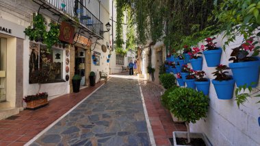 Marbella 'nın renkli saksıları ve güneşli bir günde yürüyen turistlerle dolu eski güzel caddesi - MARBELLA, SPAIN - 30 Mart 2025