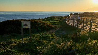 İspanya, Marbella yakınlarındaki Dunas de Artola Doğal Anıtı 'nda gün batımının keyfini çıkaran turist, ahşap bir geçitte yürüyor - MARBELLA, İspanya - 30 Mart 2025