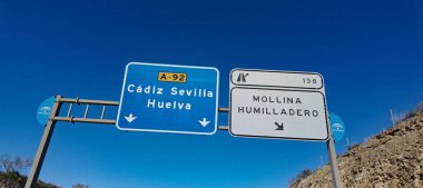 İspanya, Endülüs 'teki farklı şehirlere giden yolu gösteren işaretler, açık mavi gökyüzü altında - SEVILLE, İspanya - 25 Mart 2025