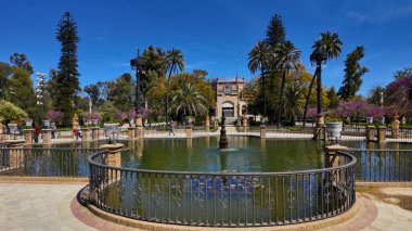 Maria Luisa Park, Seville 'de güneşli bahar gününün tadını çıkaran turistler, gölet, çeşme ve Mudejar Pavyonu - SEVILLE, SPAIN - 25 Mart 2025