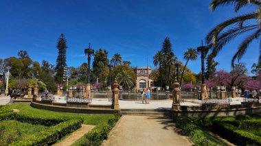 İspanya 'nın Sevilla kentindeki Plaza de America' nın mimarisine hayran olan iki turist güzel bir bahar gününde - SEVILLE, SPAIN - 25 Mart 2025