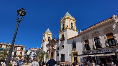 Plaza Duquesa de Parcent 'ta yürüyen turistler ve Santa Maria la Mayor kilisesi arka planda Ronda, İspanya - RONDA, İspanya - 28 Mart 2025