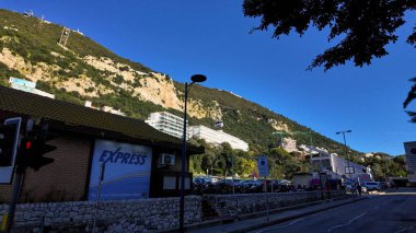 Park halindeki araçlar, binalar ve caddelerle Cebelitarık Kayası 'ndan yükselen kablo araba - GIBRALTAR, İngiltere - 31 Mart 2025