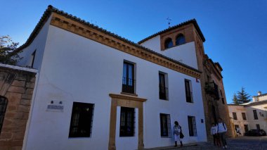 İspanya 'nın Ronda kentindeki Mondragon Sarayı' nın beyaz cephesinde mavi gökyüzünün altında yürüyen turistler - RONDA, İspanya - 28 Mart 2025