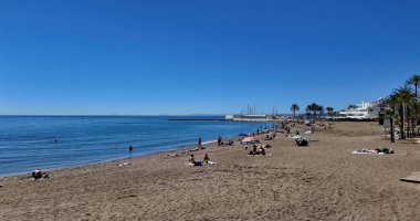 İnsanlar güneşli bir yaz gününde İspanya Marbella plajında güneşleniyor ve yüzüyorlar - MARBELLA, İspanya - 30 Mart 2025