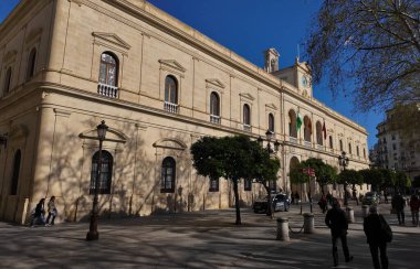 Ayuntamiento olarak bilinen Seville Belediyesi, güneşli bir günde Endülüs ve İspanyol bayrakları sergiliyor ve yakınlarda SEVILLE, İspanya - 25 Mart 2025