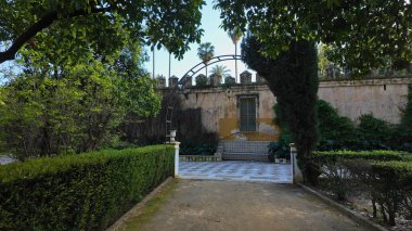 Bereketli bitki örtüsü ve eski bir duvarla çevrili, sakin bir köşeye giden yol Sevilla 'nın Murillo Bahçeleri - SEVILLE, İspanya - 25 Mart 2025