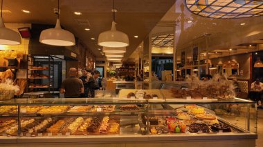 Müşteriler İspanya 'nın Sevilla kentindeki bir pastaneden hamur işi satın alırken, sergilenmekte olan çok çeşitli pasta ve pastalar - SEVILLE, SPAIN - 25 Mart 2025