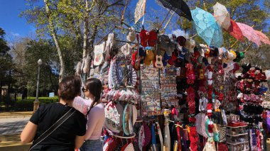 İspanya, Sevilla 'da renkli hatıralarla dolu bir sokak standına bakan iki turist - SEVILLE, İspanya - 25 Mart 2025