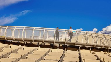 Güneşli bir günde Setas de Sevilla, Metropol Şemsiyesi 'nde yürüyen iki işadamı - SEVILLE, SPAIN - 25 Mart 2025