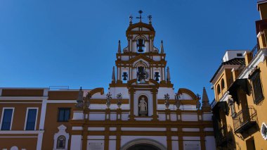 İspanya 'nın Sevilla kentindeki La Macarena Bazilikasının Barok cephesinde, berrak mavi gökyüzünün altında bir heykel ve çan kulesi - SEVILLE, SPAIN - 25 Mart 2025