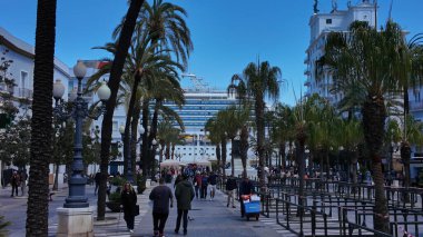 Güneşli bir günde arka planda bir yolcu gemisiyle İspanya 'nın Cadiz kentinde yürüyen insanlar - CADIZ, SPAIN - 26 Mart 2025