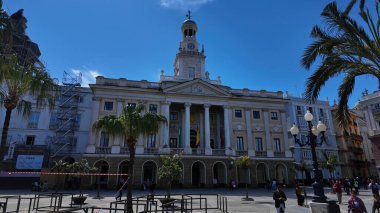 Cadiz Belediye Sarayı, San Juan de Dios meydanında rüzgarda sallanan İspanyol ve Endülüs bayraklarıyla güzel mavi bir gökyüzü altında - CADIZ, SPAIN - 26 Mart 2025