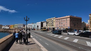 Güneşli bir günde Cadiz, Endülüs, İspanya boyunca yürüyen bir grup turist - CADIZ, İspanya - 26 Mart 2025