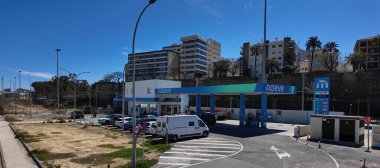 Cadiz, İspanya şehir duvarları yakınında park halindeki araçları ve karavanı olan Modern Moeve benzin istasyonu - CADIZ, SPAIN - 26 Mart 2025