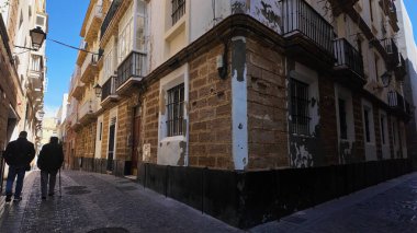 Cadiz, İspanya 'da eski binalarla dar bir sokakta yürüyen iki yaşlı adam - CADIZ, SPAIN - 26 Mart 2025