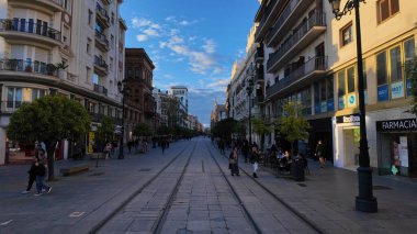 Seville 'in ana alışveriş caddesi Calle Sierpes' in keyfini çıkaran turistler ve yerliler güneşli bir öğleden sonra SEVILLE, SPAIN - 25 Mart 2025