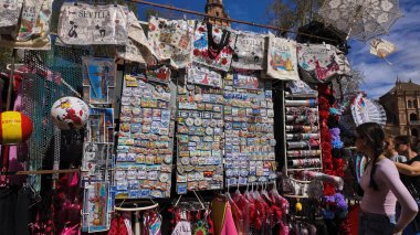 İspanya, Sevilla 'da bir hediyelik eşya standına bakan turistler, 25 Mart 2025' te Sevilla, İspanya 'da mıknatıslar, çantalar ve giysiler sergilediler.