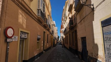 İspanya 'nın Endülüs şehrinde dar bir caddede sallanan İspanyol bayrakları - CADIZ, İspanya - 26 Mart 2025