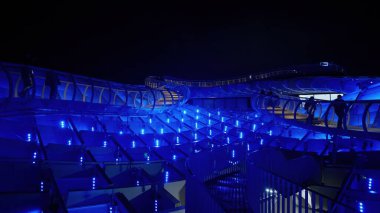 Fütüristik çatı yolu, üzerinde yürüyen insanların olduğu gece maviyle aydınlandı - SEVILLE, SPAIN - 25 Mart 2025